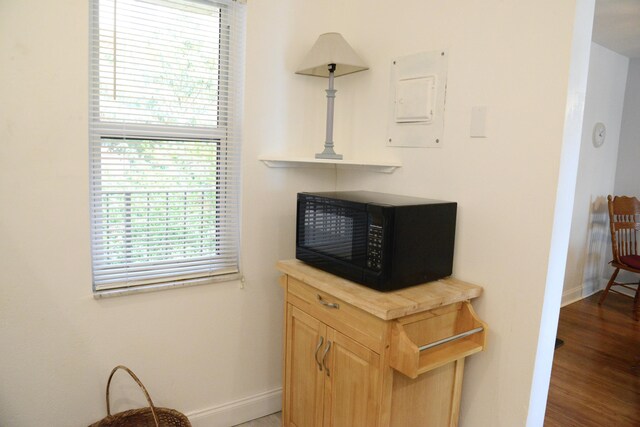 2841 Somerset Dr Unit 217, Lauderdale Lakes, FL 33311 - detailed view of black microwave, baseboards, electric panel, and wood finished floors