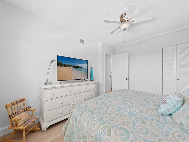 bedroom featuring a closet, visible vents, light wood finished floors, and a textured ceiling