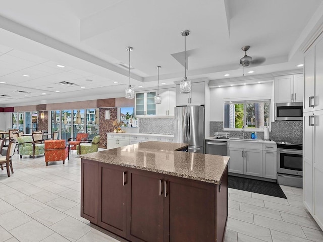 kitchen featuring tasteful backsplash, a kitchen island, appliances with stainless steel finishes, and a sink