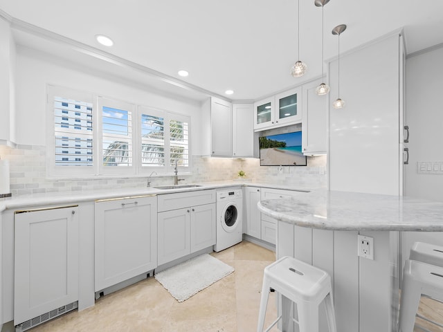 kitchen with a sink, decorative backsplash, a kitchen bar, white cabinetry, and washer / clothes dryer