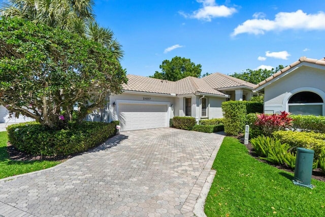 2437 NW 64th St, Boca Raton, FL 33496 - mediterranean / spanish home with a tile roof, stucco siding, decorative driveway, a front lawn, and a garage