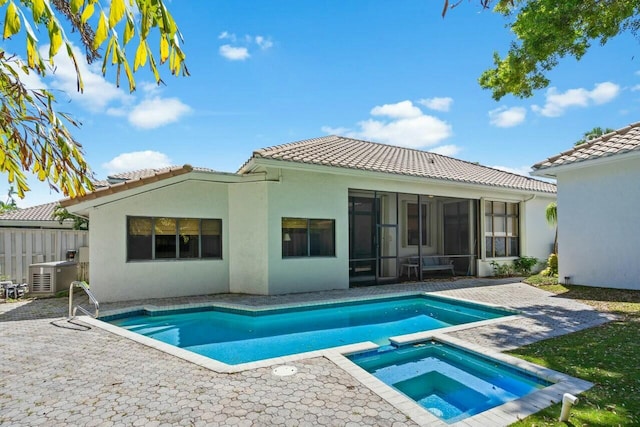 2437 NW 64th St, Boca Raton, FL 33496 - rear view of property featuring a sunroom, a tiled roof, a patio, an in ground hot tub, and stucco siding