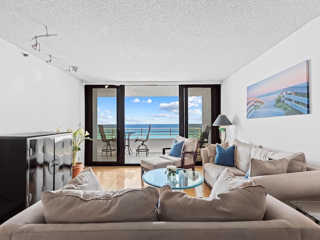 3450 S Ocean Blvd Unit 906, Highland Beach, FL 33487 - living area featuring a textured ceiling, wood finished floors, a water view, expansive windows, and rail lighting