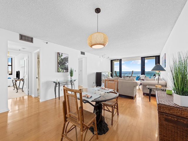 3450 S Ocean Blvd Unit 906, Highland Beach, FL 33487 - dining area with a textured ceiling, light wood-type flooring, floor to ceiling windows, and a water view