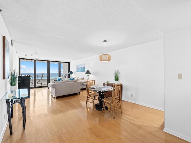 3450 S Ocean Blvd Unit 906, Highland Beach, FL 33487 - dining room featuring a textured ceiling, light wood-style floors, baseboards, a water view, and floor to ceiling windows