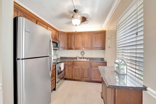 kitchen featuring stainless steel appliances, a sink, dark countertops, crown molding, and light tile patterned floors