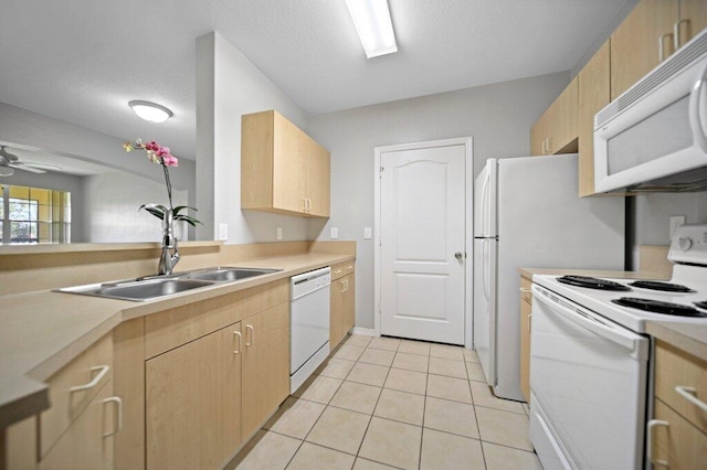 kitchen with white appliances, light countertops, a sink, and light brown cabinets