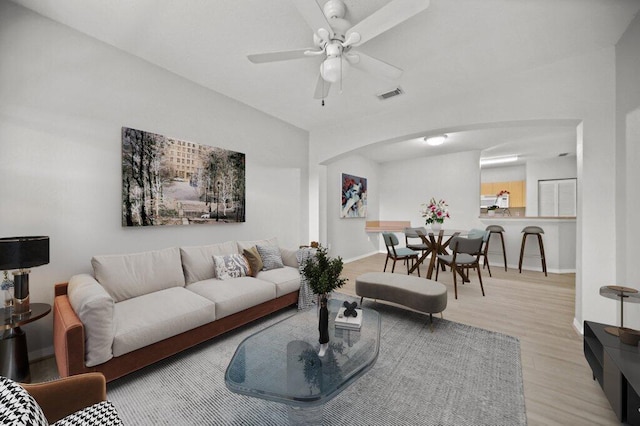 living room with ceiling fan, visible vents, arched walkways, wood finished floors, and baseboards