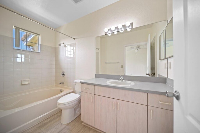 bathroom featuring a ceiling fan, wood finished floors, vanity, toilet, and washtub / shower combination