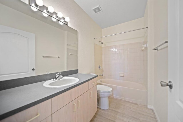 bathroom with vanity, toilet, wood finished floors, shower / bathing tub combination, and visible vents