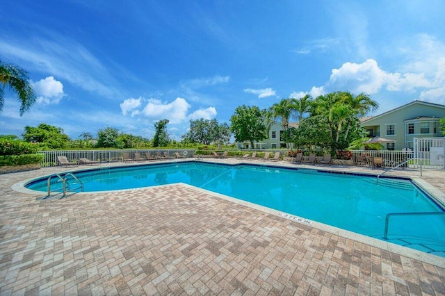 community pool with a patio area and fence
