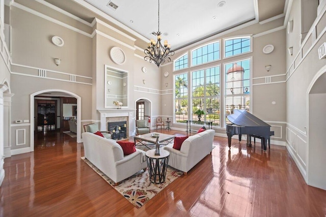 living area with visible vents, arched walkways, a high ceiling, and a premium fireplace