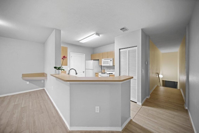 kitchen featuring white appliances, visible vents, light wood finished floors, and light countertops
