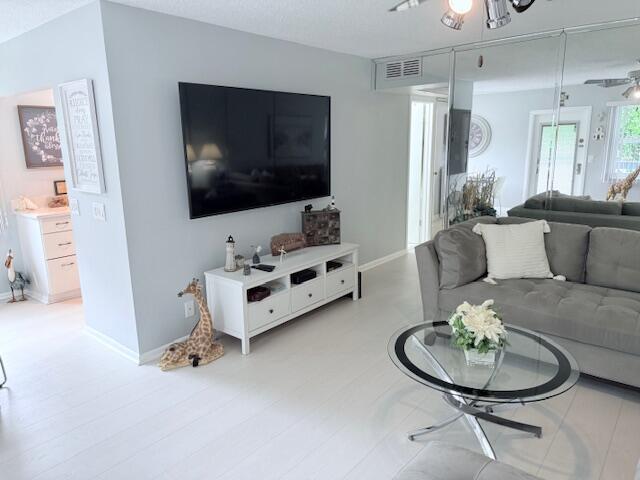 living area featuring baseboards, visible vents, and a ceiling fan