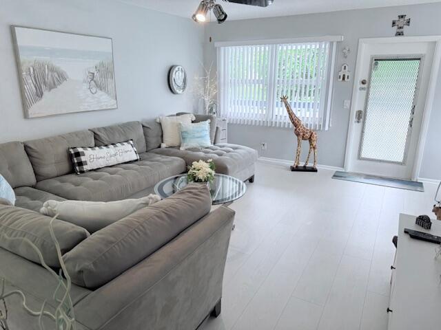 living room featuring a ceiling fan, baseboards, and wood finished floors