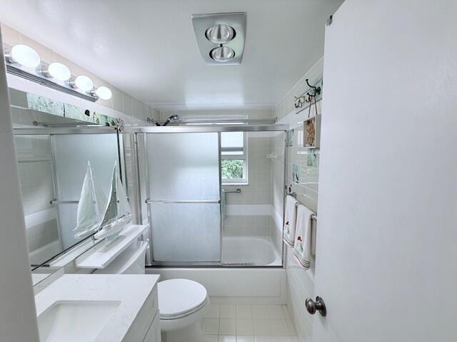 full bathroom with tile patterned floors, toilet, vanity, and shower / bath combination with glass door