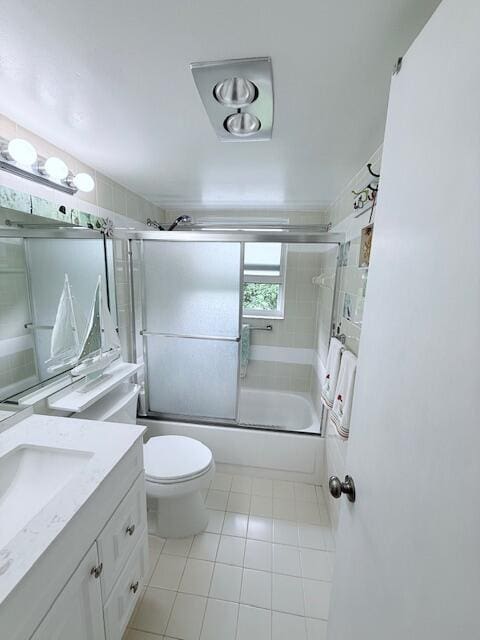 bathroom featuring toilet, vanity, enclosed tub / shower combo, and tile patterned floors