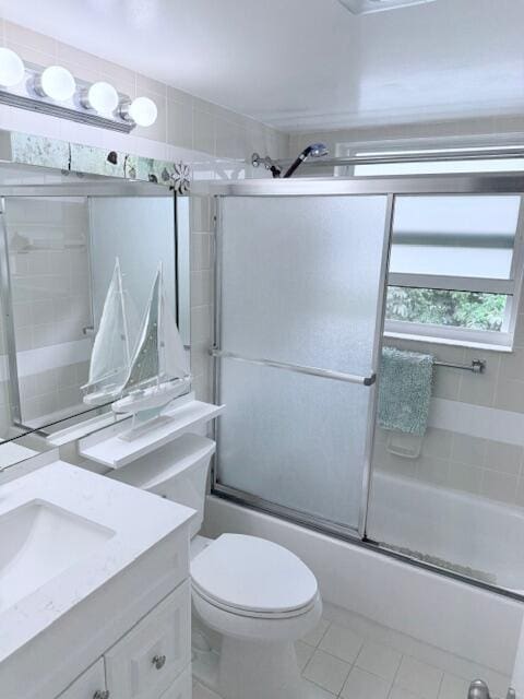 full bath with vanity, toilet, tile patterned flooring, and bath / shower combo with glass door