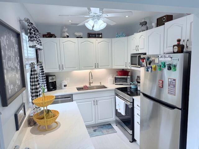 kitchen with light countertops, white cabinets, a sink, and appliances with stainless steel finishes