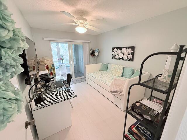 bedroom featuring a textured ceiling, access to exterior, light wood-style flooring, and ceiling fan