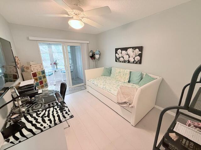living area featuring baseboards, wood finished floors, and a ceiling fan