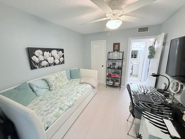 bedroom featuring light wood-type flooring, connected bathroom, ceiling fan, and visible vents