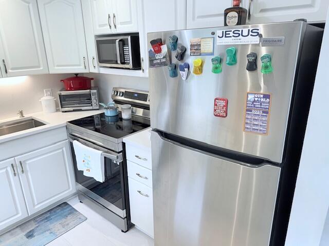 kitchen featuring a toaster, white cabinets, a sink, and stainless steel appliances