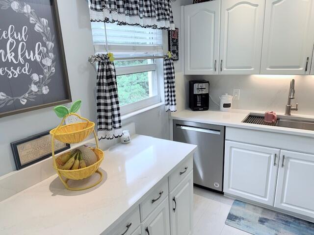 kitchen with stainless steel dishwasher, white cabinetry, and a sink