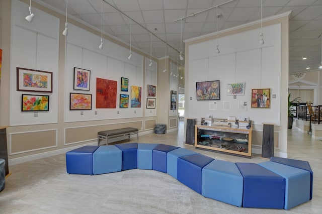 living room featuring a high ceiling, rail lighting, and a decorative wall