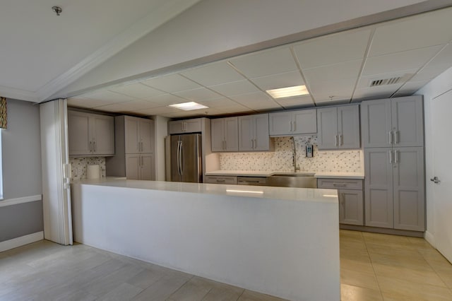 kitchen with gray cabinets, light countertops, freestanding refrigerator, tasteful backsplash, and visible vents