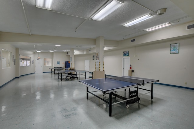recreation room featuring baseboards, visible vents, and concrete floors