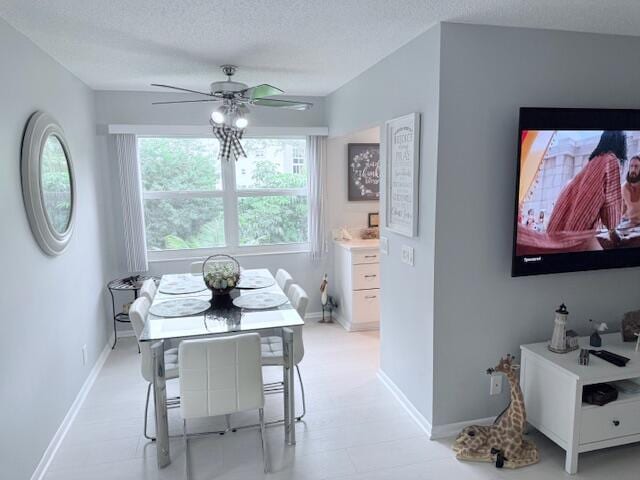 dining space with baseboards, ceiling fan, and a textured ceiling