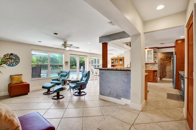 living area featuring baseboards, light tile patterned floors, ceiling fan, and visible vents