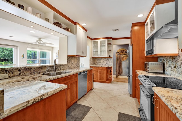 kitchen featuring open shelves, exhaust hood, a sink, appliances with stainless steel finishes, and light stone countertops