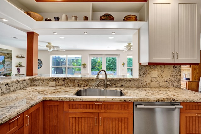 kitchen with a sink, ceiling fan, dishwasher, and light stone countertops