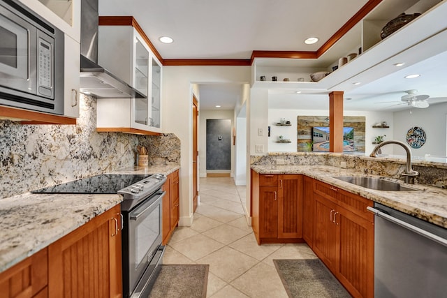 kitchen featuring wall chimney exhaust hood, a sink, appliances with stainless steel finishes, brown cabinets, and light tile patterned flooring