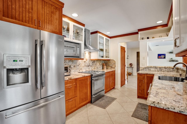 kitchen featuring tasteful backsplash, light tile patterned flooring, wall chimney exhaust hood, appliances with stainless steel finishes, and a sink