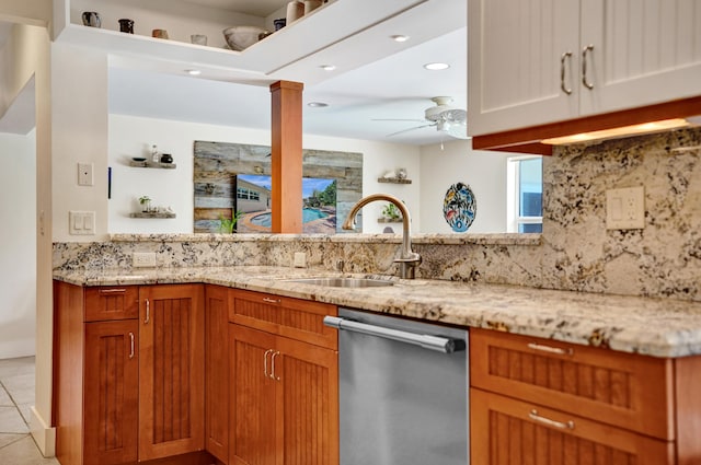 kitchen with a sink, a ceiling fan, backsplash, stainless steel dishwasher, and light stone counters
