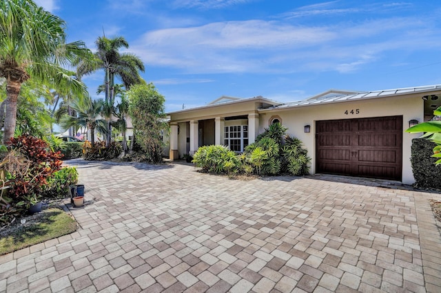 ranch-style house with an attached garage, decorative driveway, and stucco siding