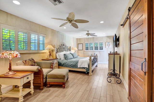 bedroom featuring ceiling fan, light wood-type flooring, visible vents, recessed lighting, and a barn door