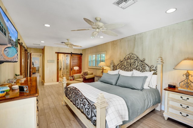 bedroom featuring light wood-style flooring, recessed lighting, visible vents, and a barn door