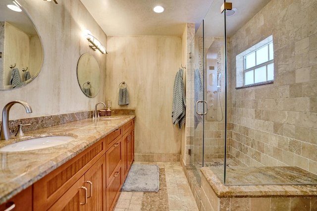 full bath featuring a sink, double vanity, stone finish floor, and a stall shower