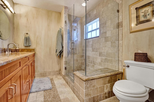 bathroom featuring stone tile floors, vanity, toilet, a stall shower, and baseboards