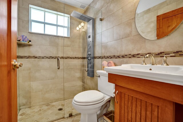 full bath with vanity, toilet, tile walls, a stall shower, and backsplash