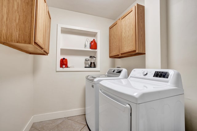 washroom featuring light tile patterned floors, baseboards, cabinet space, and washing machine and dryer