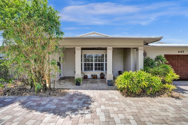 view of front of property with a garage, stucco siding, and covered porch
