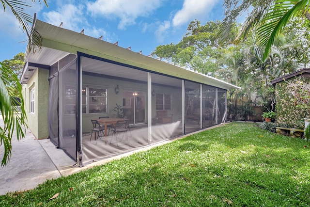 630 Glenridge Dr, West Palm Beach, FL 33405 - back of house featuring a lawn, stucco siding, a sunroom, and a patio