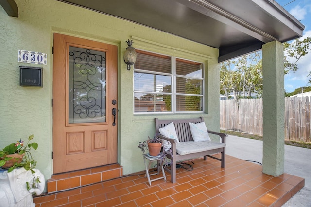 630 Glenridge Dr, West Palm Beach, FL 33405 - property entrance with stucco siding, a porch, and fence