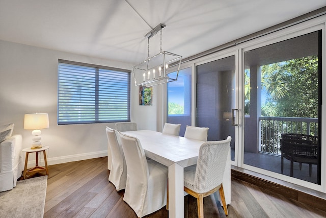 dining area featuring baseboards, hardwood / wood-style flooring, and an inviting chandelier
