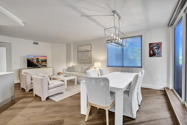 dining space featuring visible vents, baseboards, a chandelier, and wood finished floors